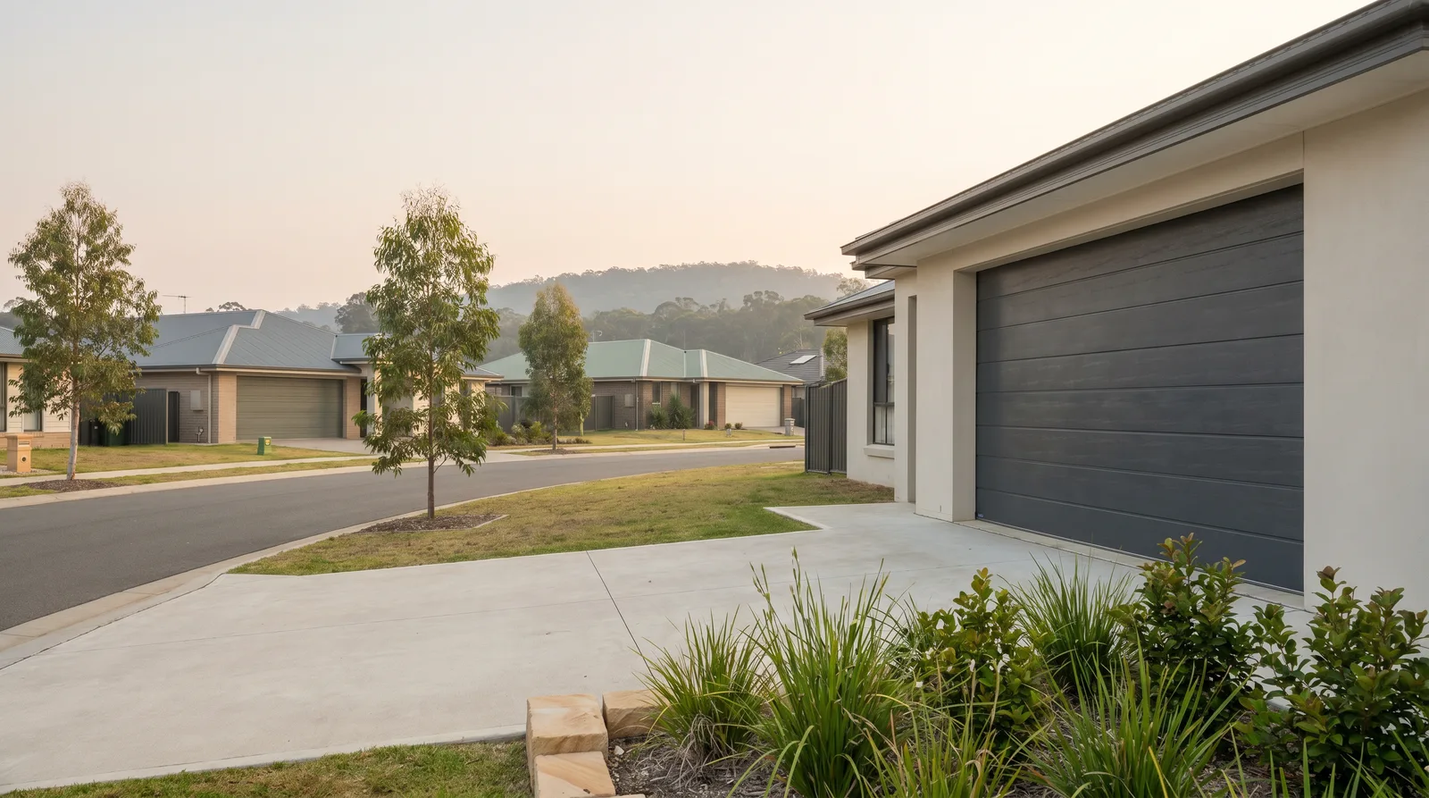 A new charcoal flat-profile sectional door on a rendered Cameron Park estate home